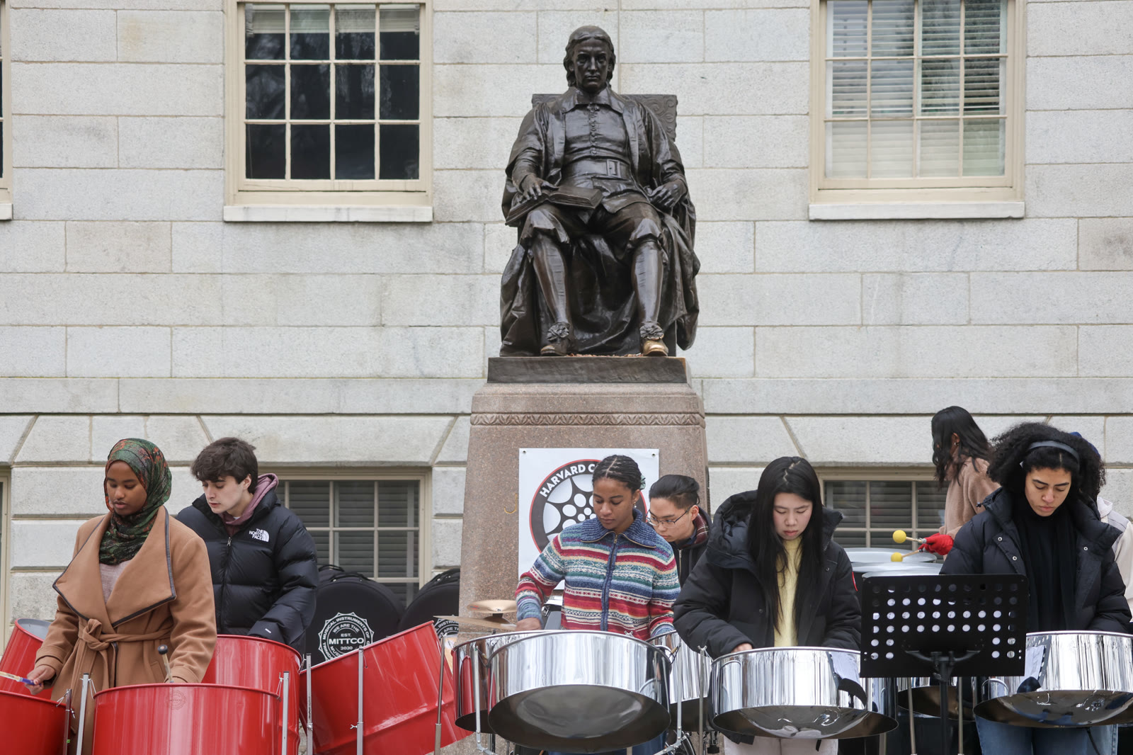 The ensemble performing on steelpans beneath the John Harvard statue in Harvard Yard.
