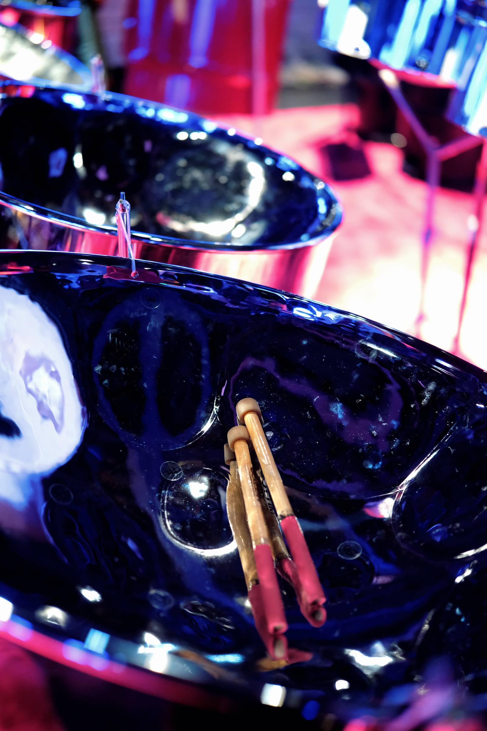 Steelpan mallets resting inside a polished pan during rehearsal.