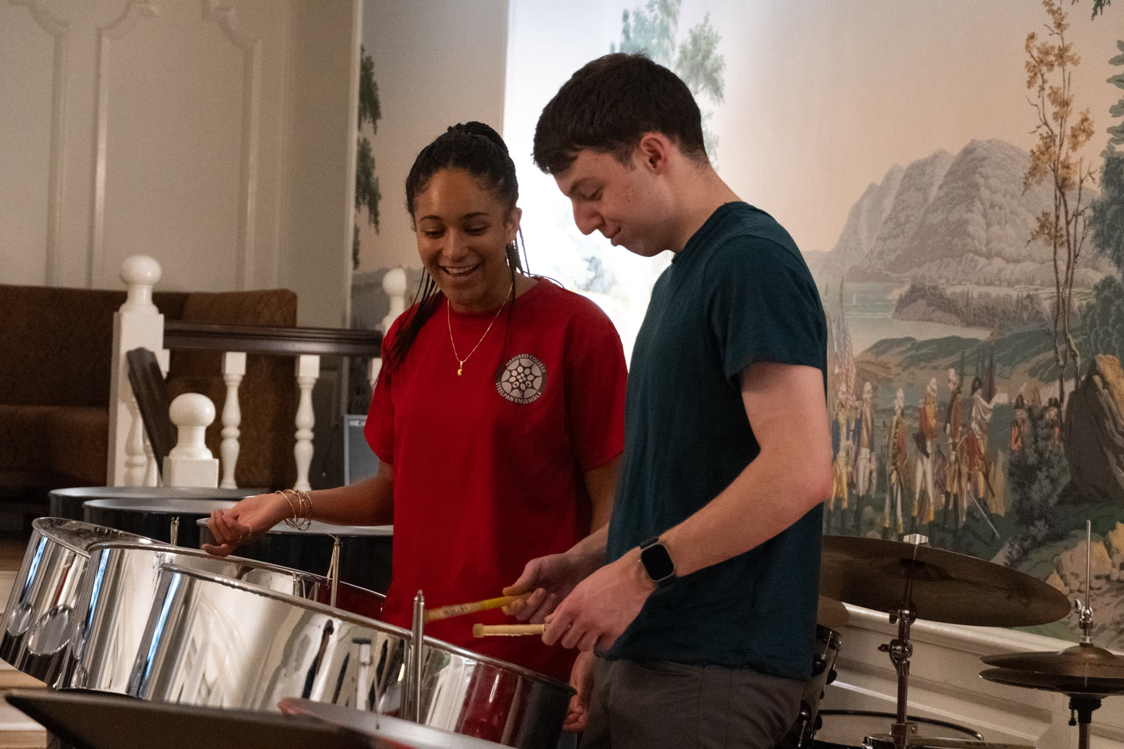 One member teaching another a pattern on a tenor pan at rehearsal.