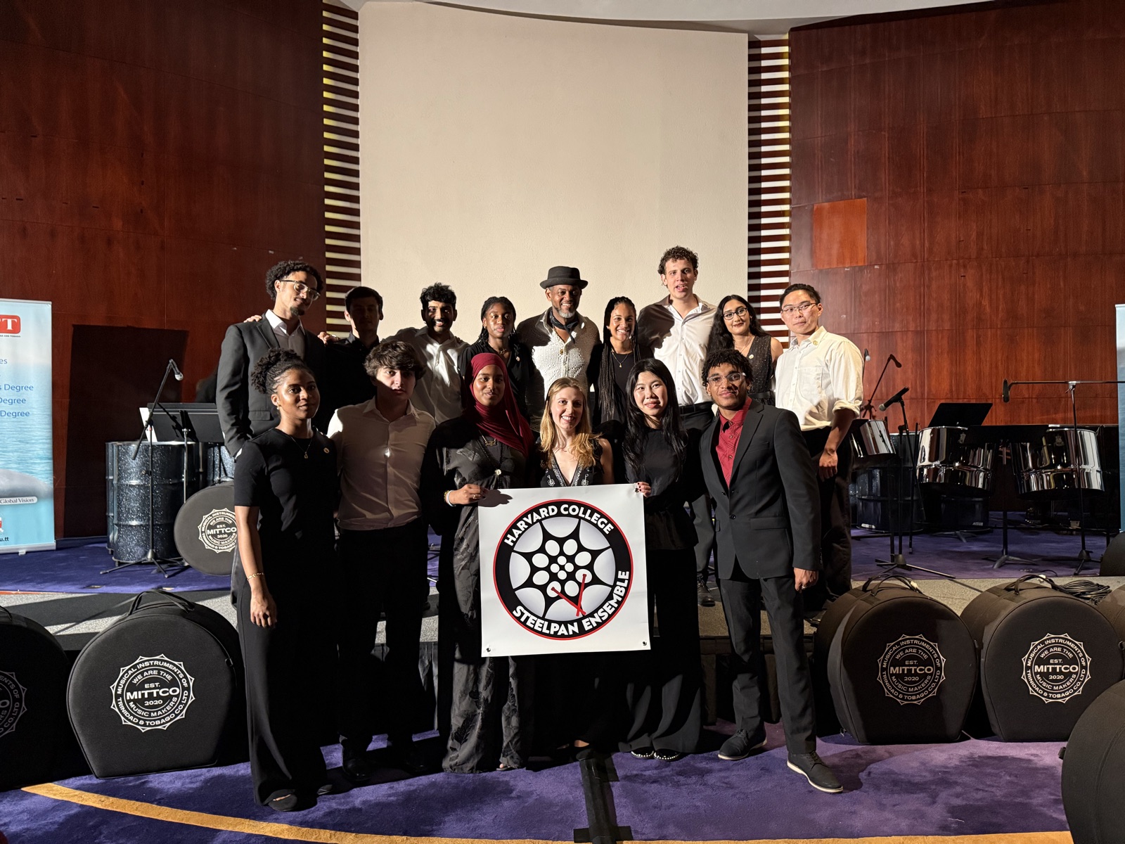 The ensemble on stage in concert dress, holding their banner after the show.